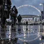 Quel stade visiter a londres : Wembley, visiteurs sous la pluie avec panneaux directionnels